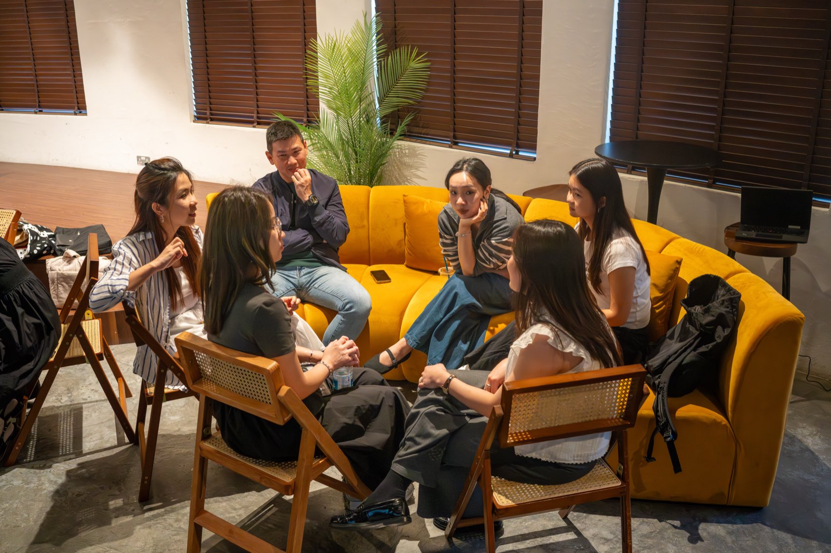A small group in conversation on low seating in a studio space, away from the office.